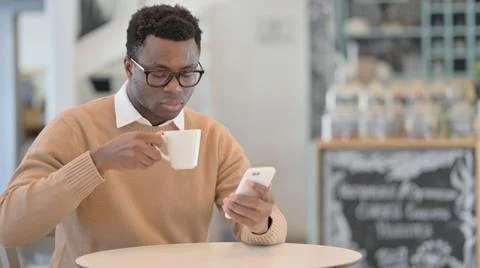 African Man Drinking Coffee Using Smartphone Stock Photos