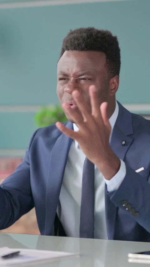 African Man feeling Angry while Sitting in Office, Vertical Video Video stock 339575136