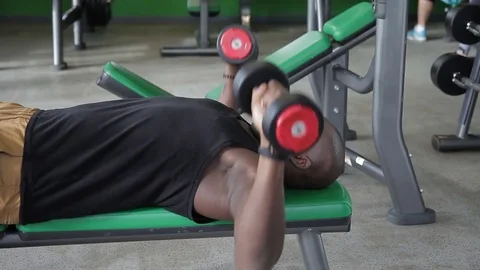 African man in gym do an exercise of dumbbell bench press lying down. Video stock 83407296