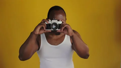 African man is holding an old camera and taking a photo.  Stock Footage 201292020