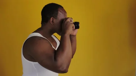 African man is holding an old camera and taking a photo. Black man in a whit Stock Footage 201292067