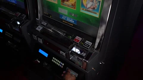 African man inserting a playing card into a slot machine at a casino Stock Footage 256790072