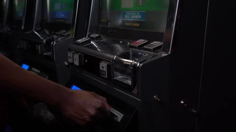 African man inserting a playing card into a slot machine at a casino Stock Footage 256790171