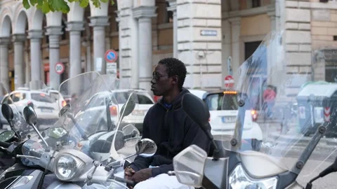 African man looking away contemplating on the scooter in the street Stock Footage 217821015