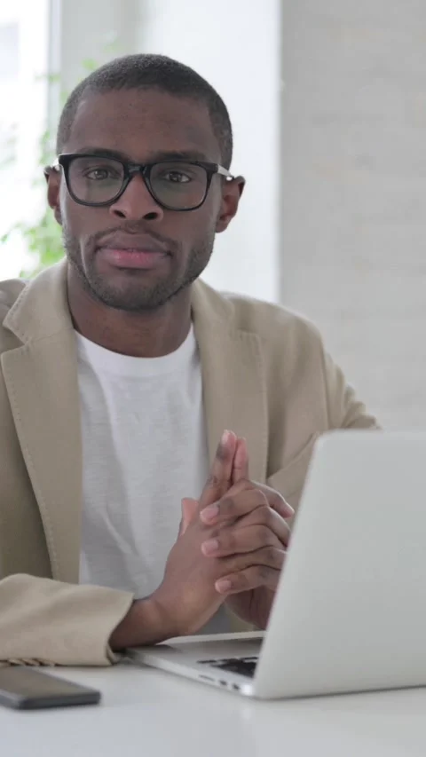 African Man Looking at Camera while using Laptop in Office, Vertical Video Stock Footage 337350027