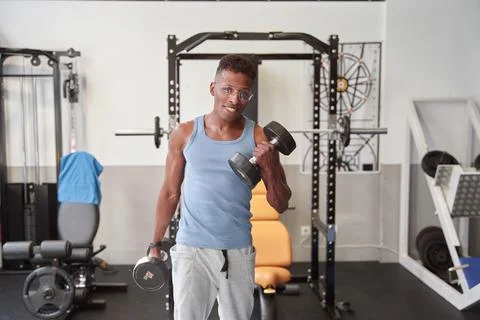 African man looking at the camera while doing weights at the gym Foto stock