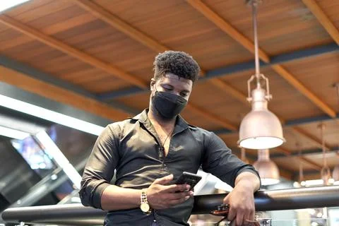 African man in mask using the mobile in a shopping mall Stock Photos