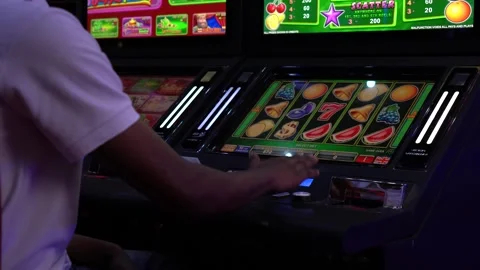 African man playing slot machine games at a casino 스톡 동영상 256793479