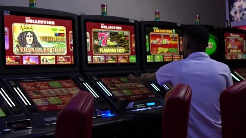 African man playing slot machine games at a casino Stock Footage 256794888