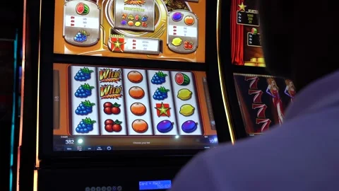 African man playing slot machine games at a casino Stock Footage 256794891