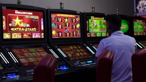 African man playing slot machine games at a casino Stock Footage 256795207