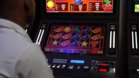 African man playing slot machine games at a casino Stock Footage 256795211