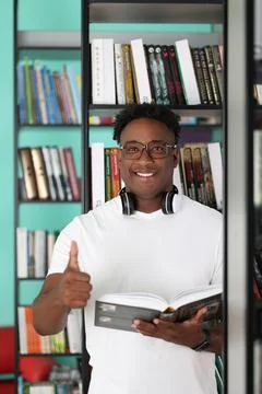 African man posing in bookstore while choosing interesting book from shelf Foto stock
