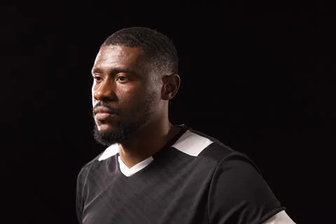 African man posing under studio lighting wearing black athletic shirt with white Stock Photos