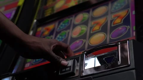 African man pressing "Start" button on a slot machine in a casino Stock Footage 256791524