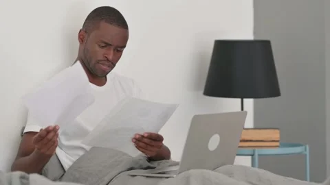 African Man Reading Documents while Sitting in Bed at Home Stock-Footage 287909659