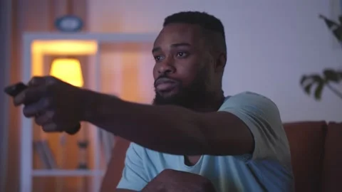 African man with remote control watching tv at home Stock Footage 145852282