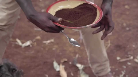 A African man scoops coffee grounds into pot of boiling water Stock Footage 155465864