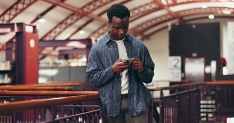 African man, scrolling and reading in library with phone, notification and email Stock Footage 318278416