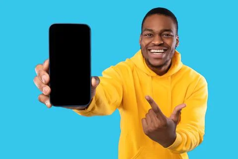 African Man Showing Cellphone With Blank Screen Over Blue Background Stock Photos
