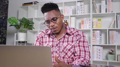 African man sitting and working in a room at home. Feeling serious Video stock 165438448
