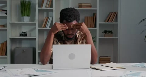 African man sitting at the office, hardworking, looking tired and stressed. Stock Footage 253825402