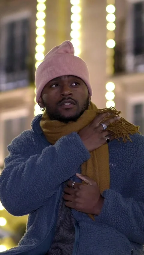 African man sitting outdoors during Christmas night Stock Footage 283336778
