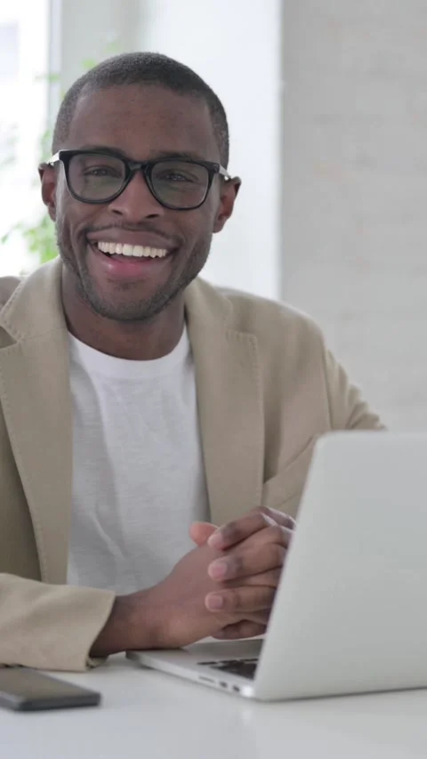 African Man Smiling at Camera while using Laptop in Office, Vertical Video Stock Footage 337350068