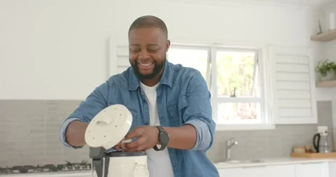 African man smiling, reaching and aligning white lid on cooker at kitchen Vídeo Stock 340969414