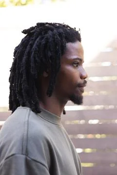 African man standing in backyard facing right, wearing olive sweatshirt and stud Stock Photos