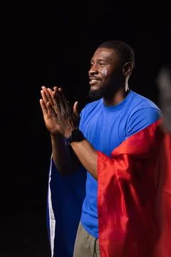 African man standing clapping studio wearing blue tee, red sash and smartwatch, Stock Photos