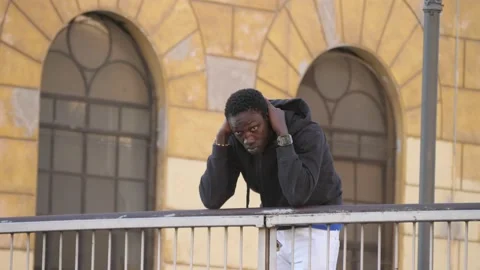 An african man standing leaning on the railing of a bridge deep in thought Stock Footage 217811194