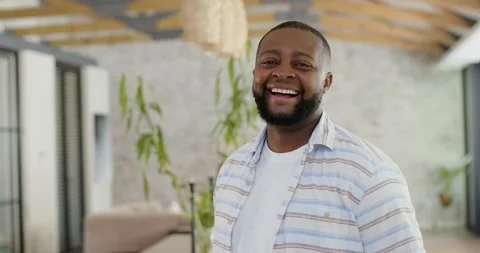 African man standing in loft in striped shirt and white tee, reacting to Stock Footage 340981519