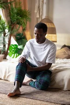 African man suffering from pain in leg. Stock Photos