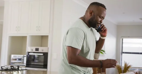 African man taking phone call, walking to dining table, grabbing pen and writing Stock Footage 337706237