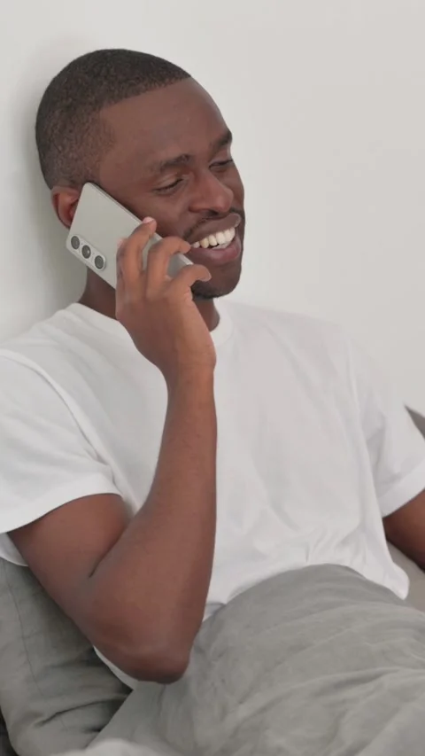 African Man Talking on phone while Sitting in Bed Stock Footage 301855731