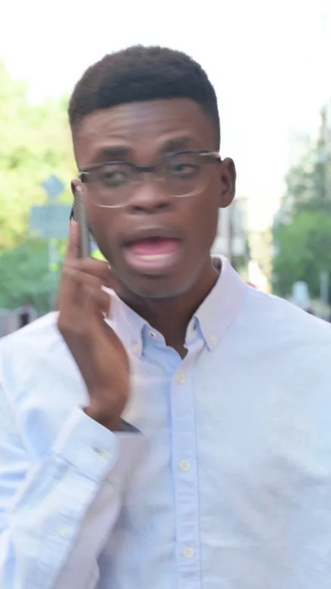 African Man Talking on Phone while Walking on the Street, Vertical Video Stock Footage 340022796
