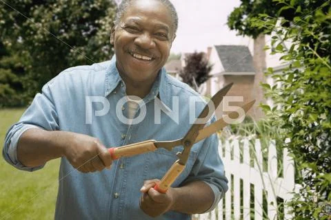 African man trimming hedges outdoors Stock Photos
