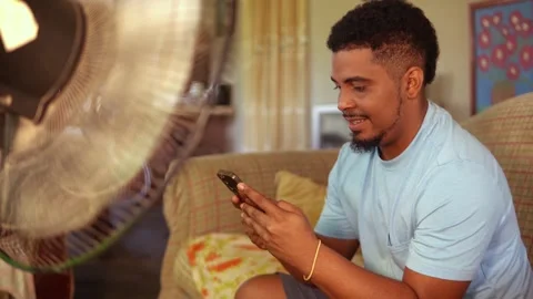 African man using a smartphone at home Stock Footage 328176468