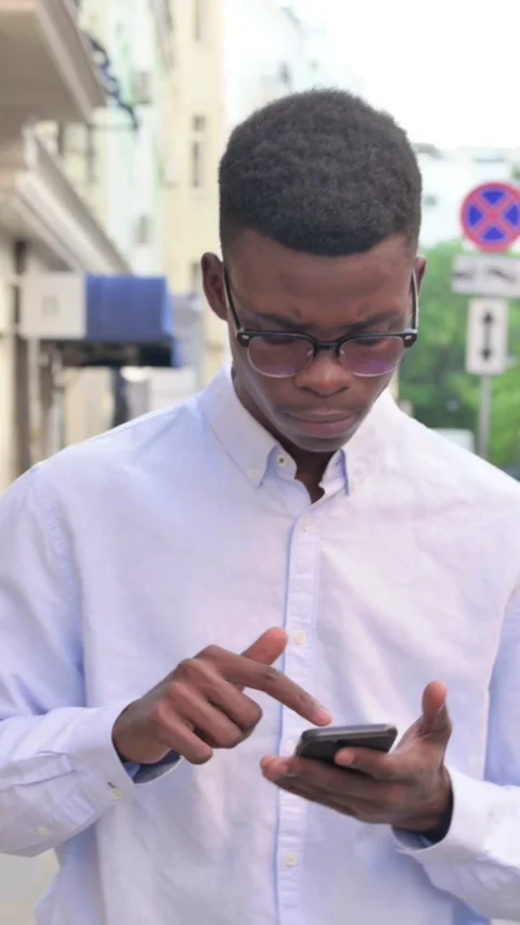 African Man using Smartphone while Walking on the Street, Vertical Video Stock Footage 340021935