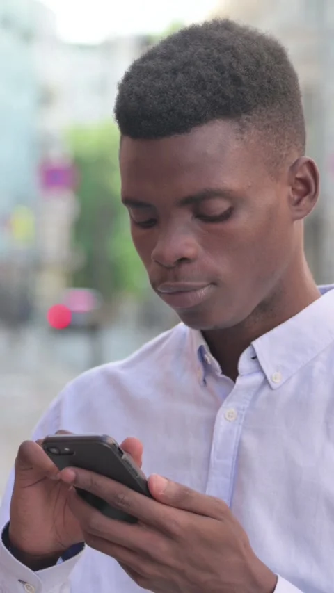African Man using Smartphone while Standing Outdoor, Vertical Video Stock Footage 340024132