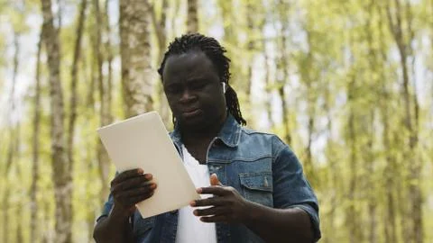 An african man using the tablet in the forest. wireless or future technology Stock Photos
