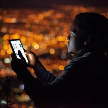 African man using a tablet at night with cityscape background Stock Photos