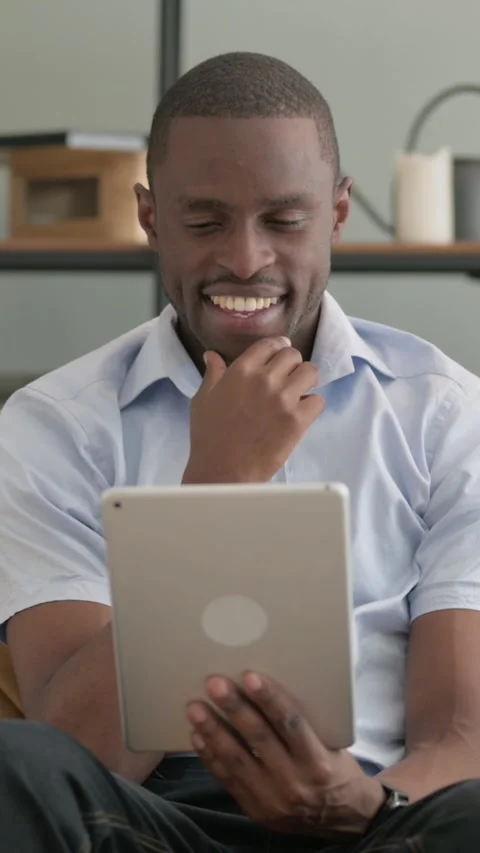 African Man Using Tablet while Sitting on Sofa at Home Video stock 301856347