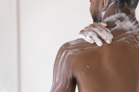 African man washes in shower, back and shoulder view Stock Photos