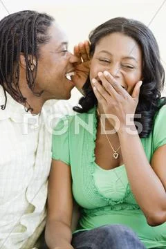 African Man Whispering In Woman's Ear