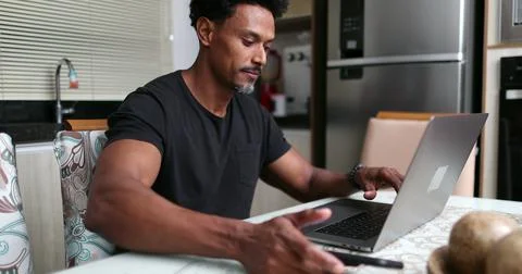 African man working from home using smartphone and laptop computer Foto stock