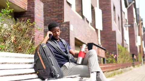 African man working with laptop sitting on a city bench Stock Footage 282572694