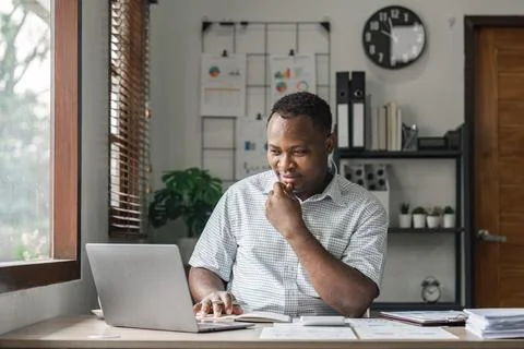 African man in writing notes in notebook watching webinar video course, serious Stock Photos