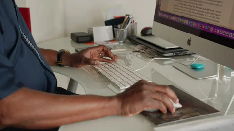 African man's hand moving computer mouse, writing at desk in his home Stock Footage 336529640